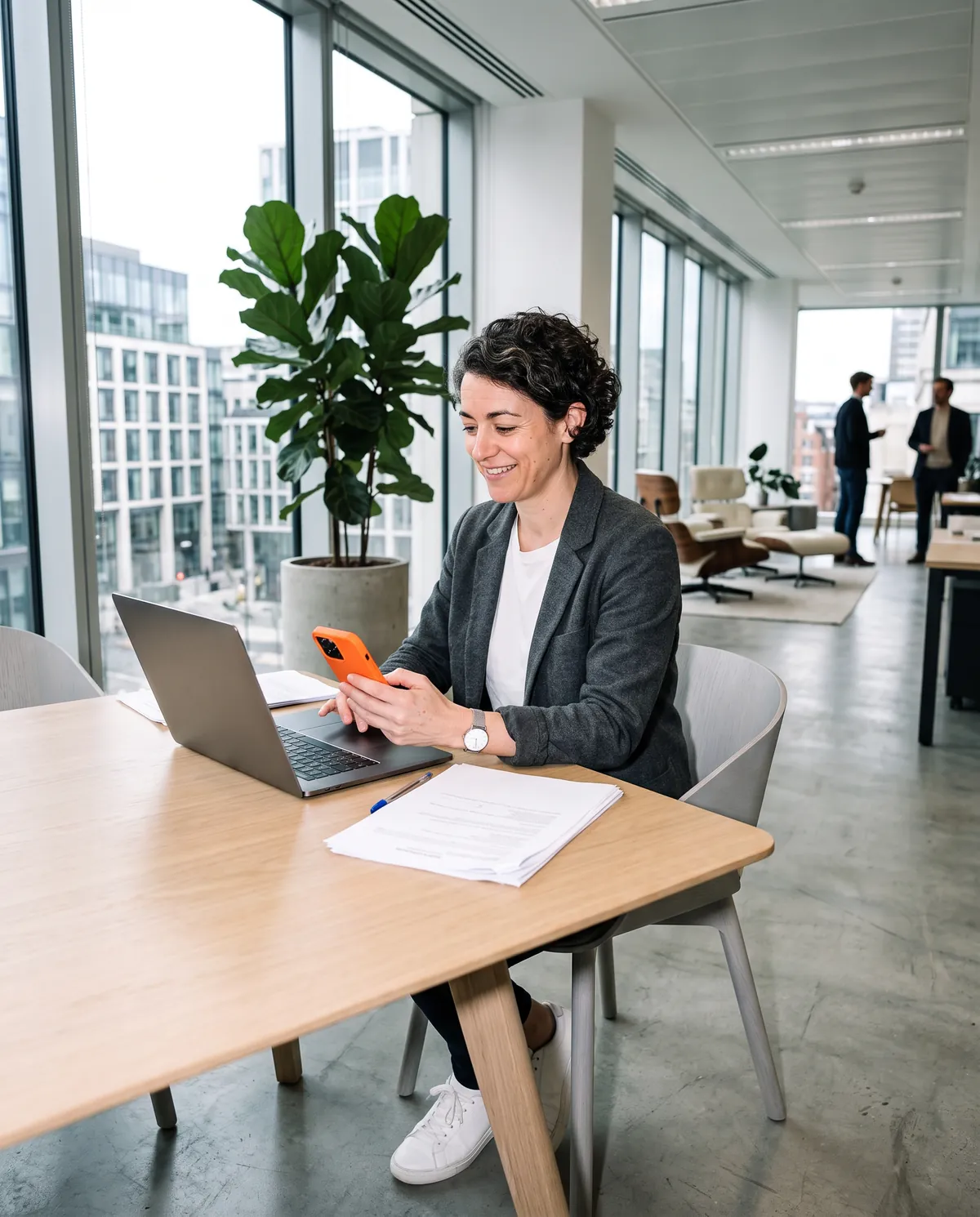 A founder alone at a desk in a modern London office, reading a benchmark result on a phone